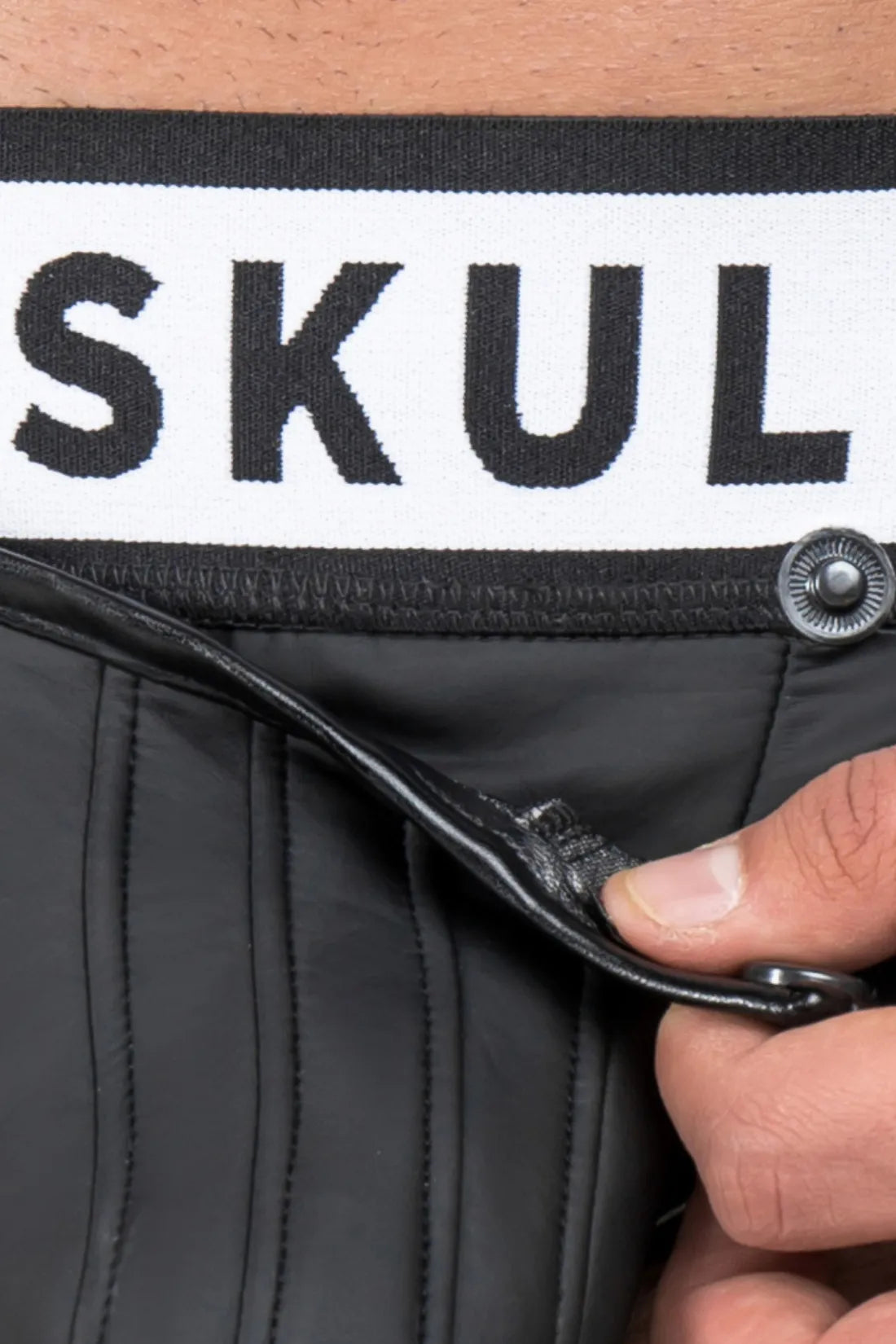 Slip aspect caoutchouc. Pochette détachable. Arrière ouvert. Noir